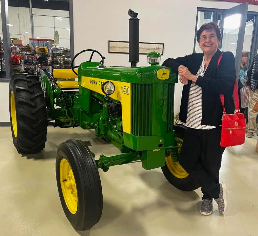 59.jpg - Mary Coulombe stands besides a John Deere tractor.