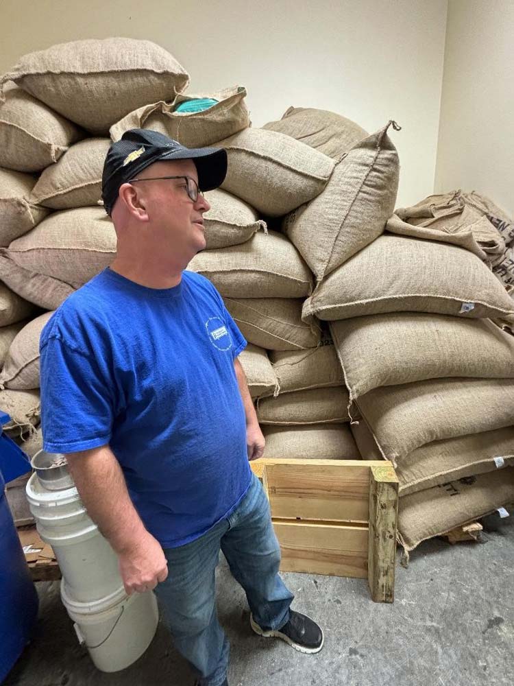63.jpg - Steve Taylor, owner of Taylor-Made Chocolate Factory in Chester, stands next to the huge bags of cacao beans used to create his products.